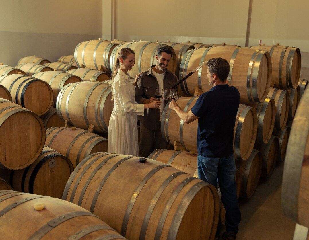 Casal degustando vinho junto às barricas